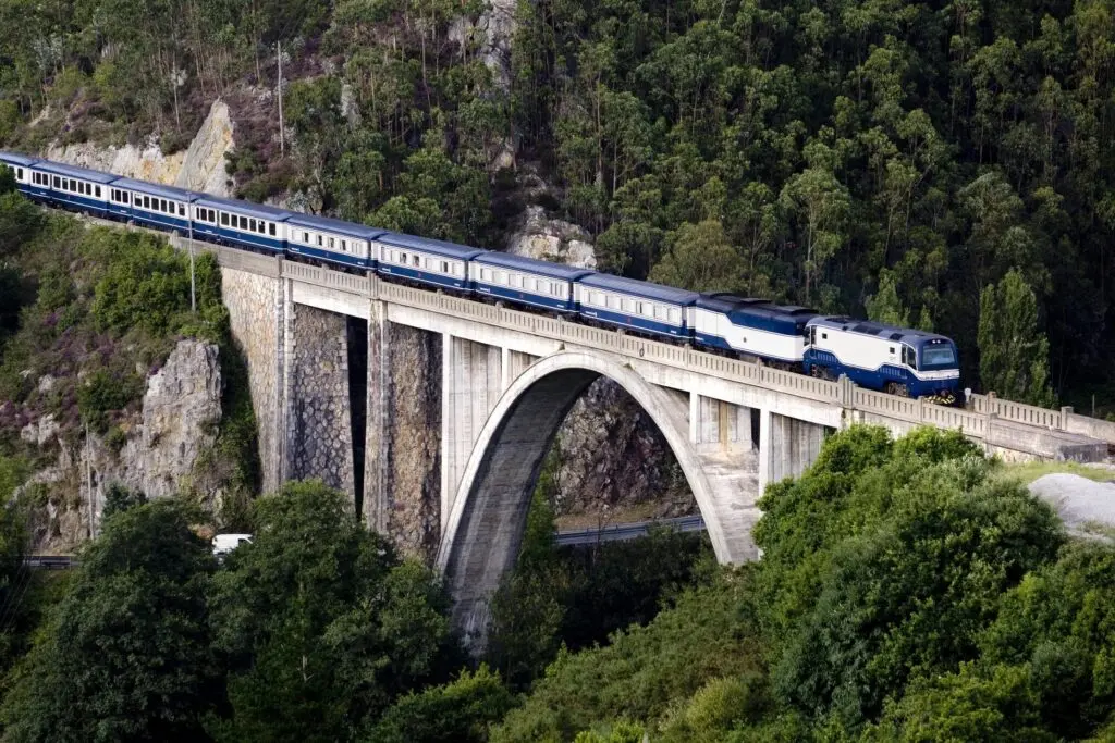 El Transcantábrico on an arch bridge through green hills