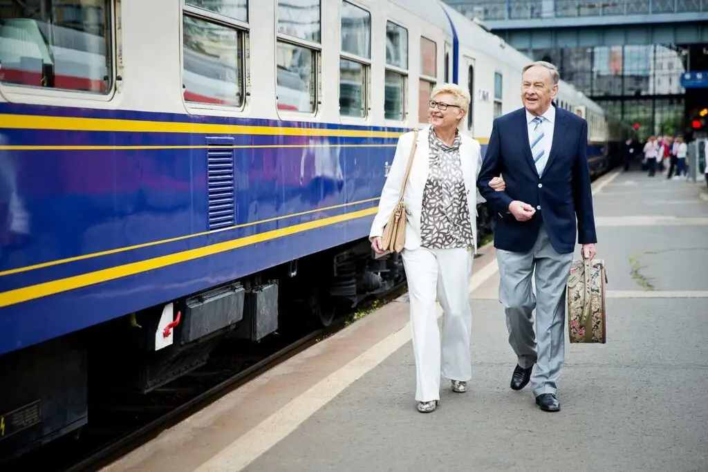 Couple walking along a station platform beside blue and cream luxury train carriages
