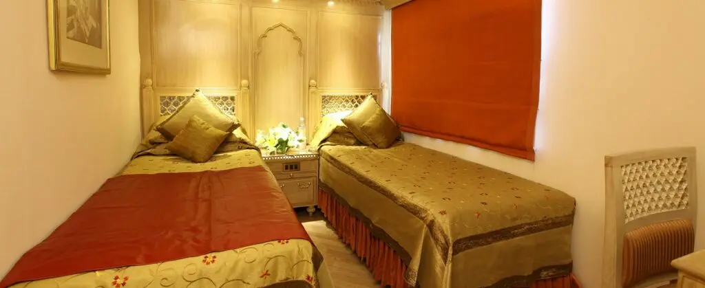 Deluxe Cabin with twin beds in gold embroidered covers and a carved jali headboard