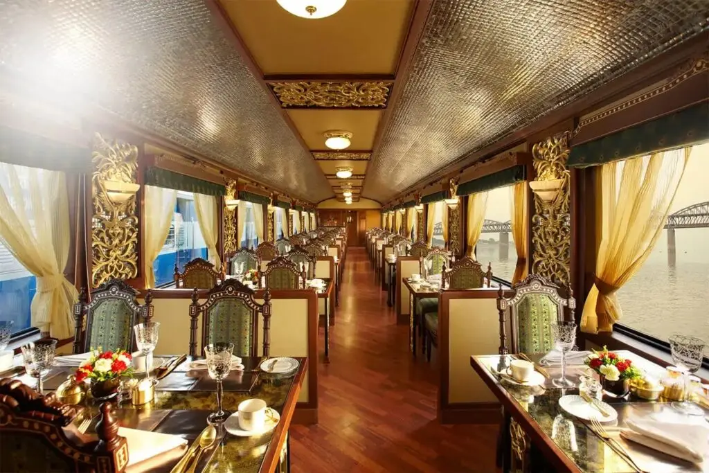 Mayur Mahal dining car with gilded peacock panels, green chairs and tables set with crystal