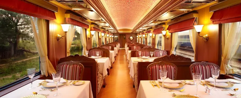 Rang Mahal dining car with painted floral ceiling, striped chairs and tables set with gold chargers