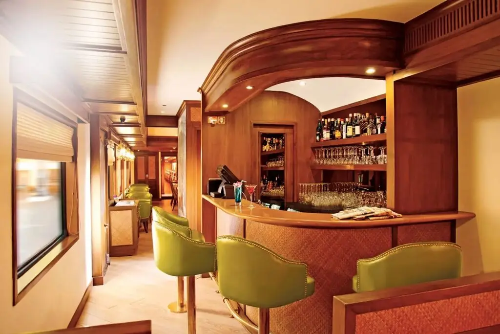 Safari Bar car with curved wooden counter, green leather stools and shelves of bottles