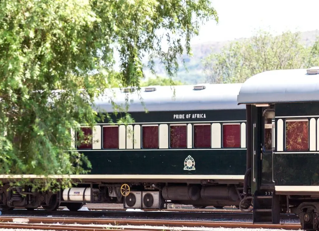 Green and cream Rovos Rail carriages under trees
