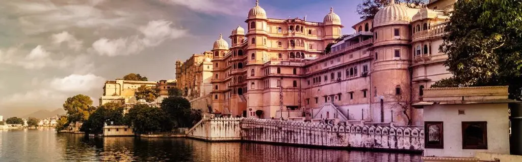 Udaipur City Palace on the shore of Lake Pichola under a dramatic evening sky